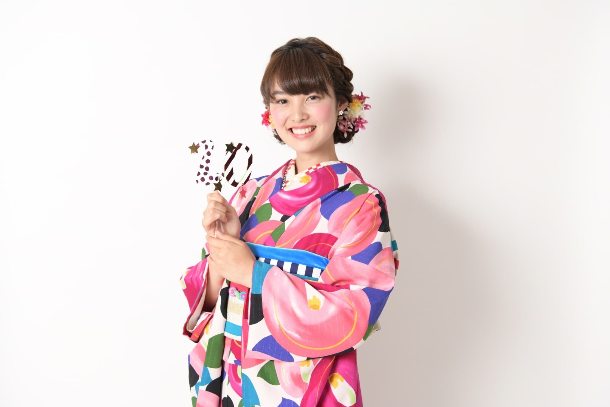 ピンクの着物を着た若い女性が20の小物を持っている