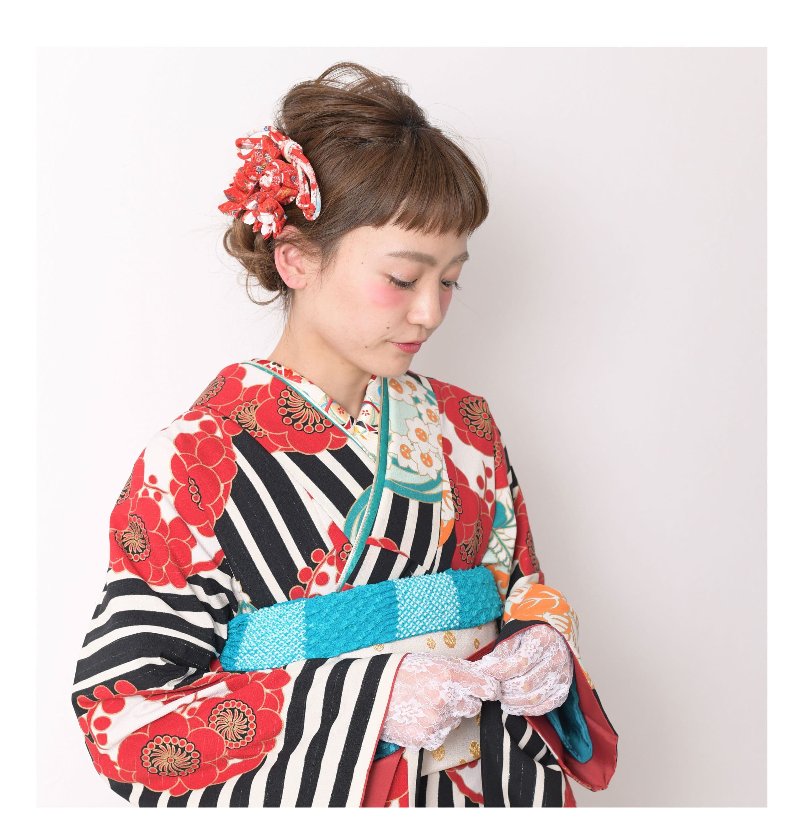 白レースの手袋を付け、赤と黒の柄着物を着た若い女性